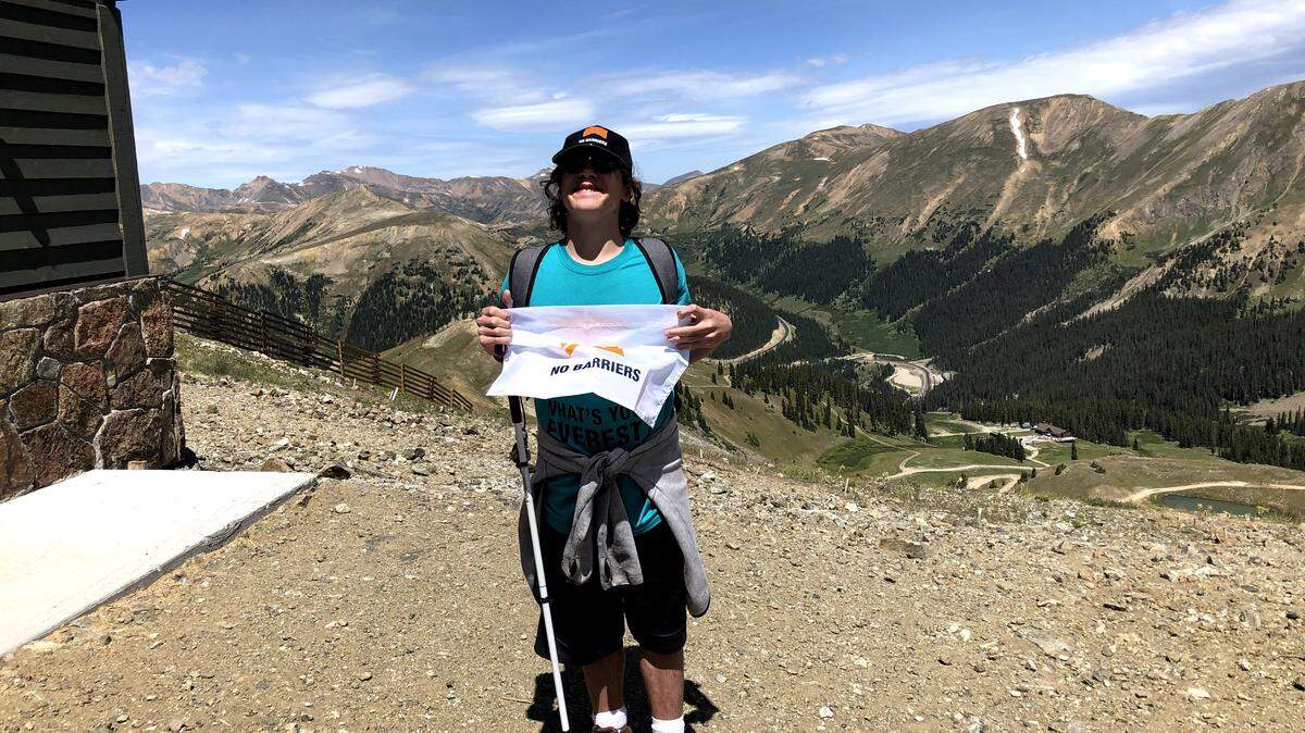 Isaac McBurney, 15, stands at the summit of the mountain he climbed in August as part of an event with the non-profit No Barriers.