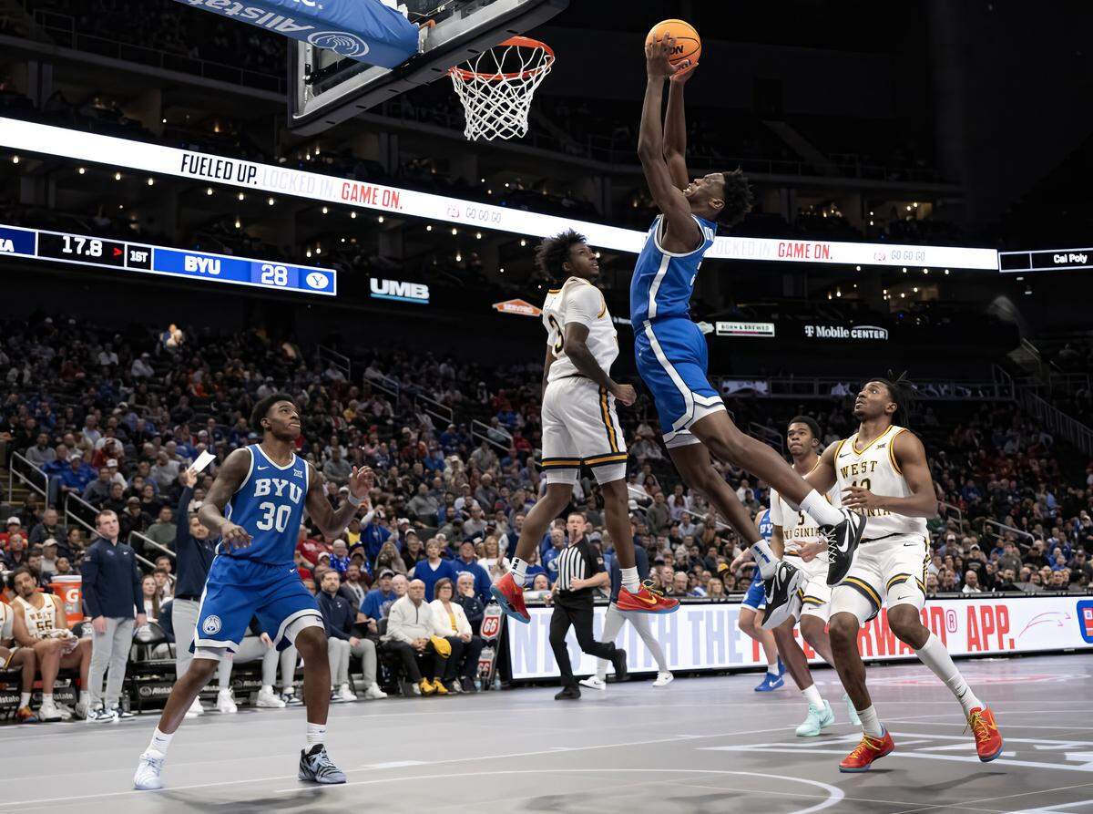BYU Cougars forward AJ Dybantsa (3) goes for a slam dunk as West Virginia Mountaineers guard Honor Huff (3) defends during the first half of the Big 12 Men's Basketball Tournament at T-Mobile Center on Wednesday, March 11, 2026, in Kansas City.
