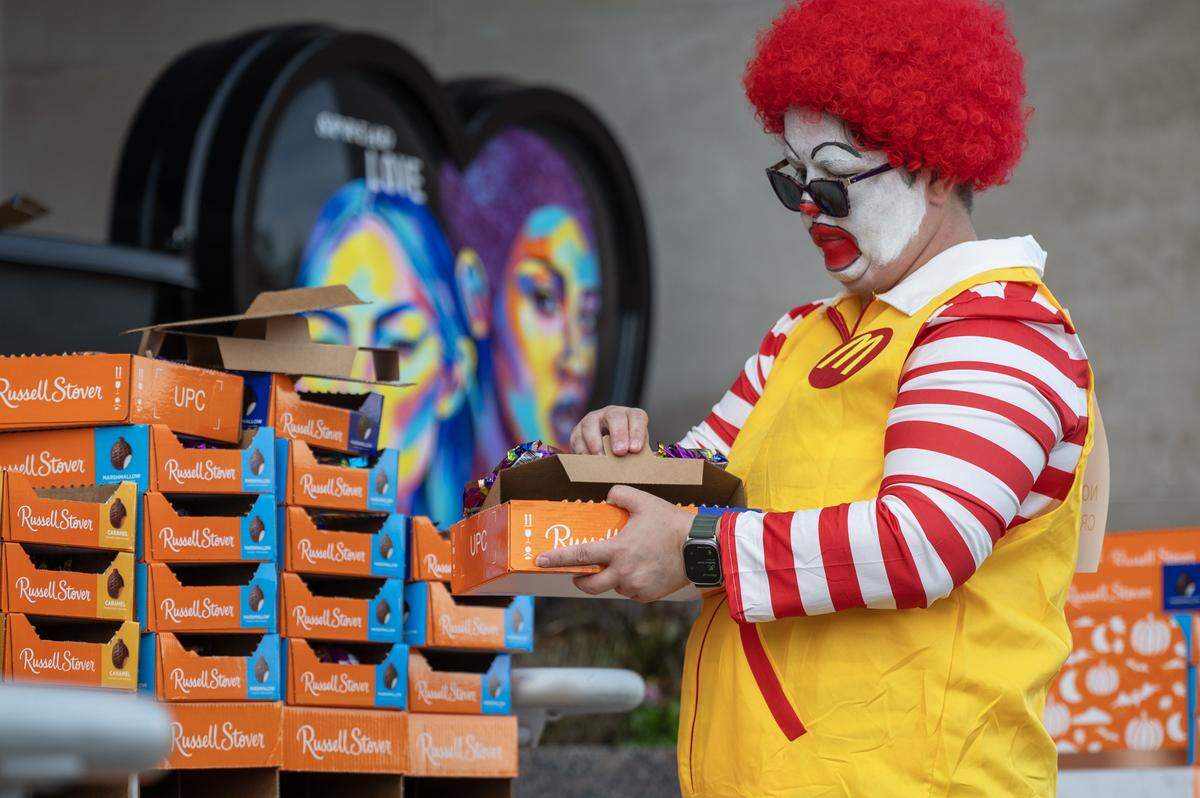 Dawn Wyatt, dressed as Ronald McDonald, opens a box of candy during Russell Stover's annual Halloween candy giveaway at the company's headquarters on Friday, Oct. 31, 2025, in Kansas City.