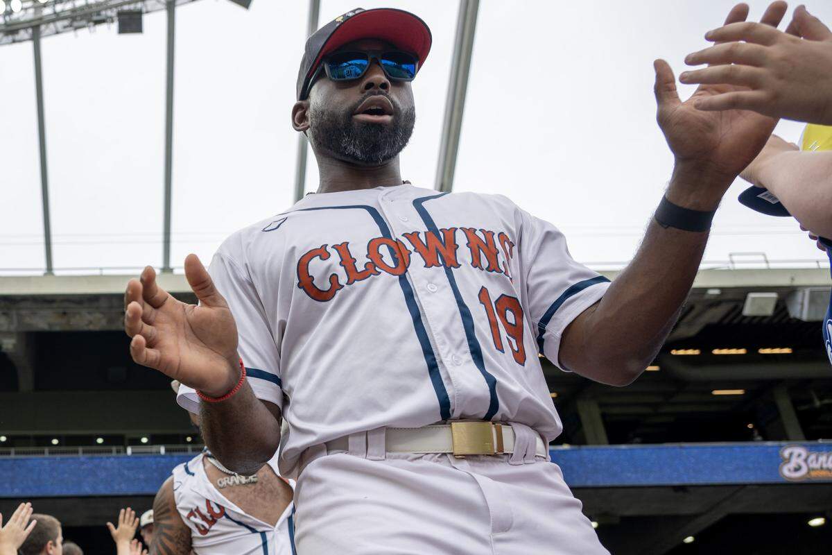 Indianapolis Clowns outfielder Jackie Bradley Jr. (19) high-fives fans before a Banana Ball game against the Indianapolis Clowns at Kauffman Stadium on Saturday, May 30, 2026, in Kansas City.