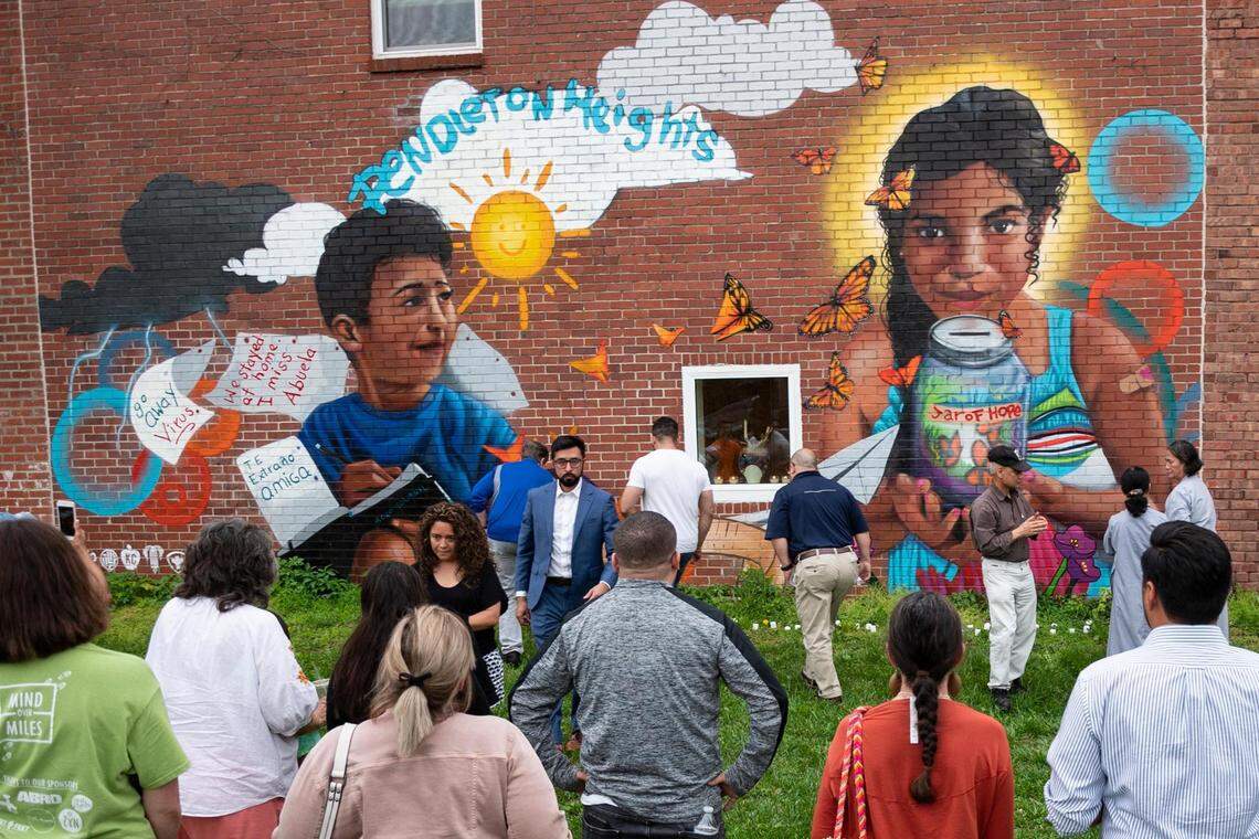 People gather in front of the mural at the Latinx Education Collaborative for the “Vigilia para nuestros niños” (Vigil for Our Children), held to honor the lives of children lost through violence in schools on Tuesday, May 31, 2022, in the Pendleton Heights neighborhood in Kansas City.