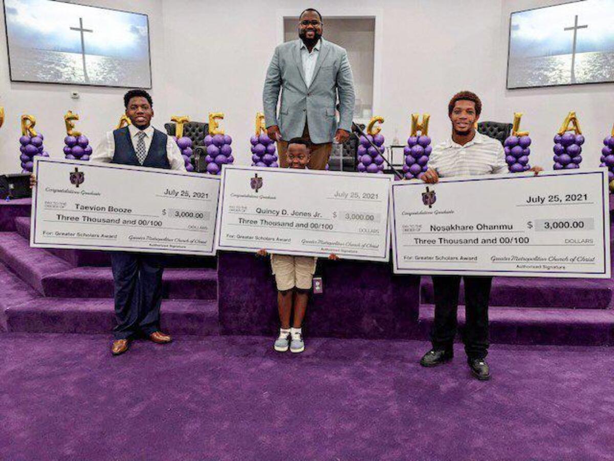 Branden Mimms at the Greater Metropolitan Church of Christ with scholarship recipients; the child in the middle standing in for his brother.