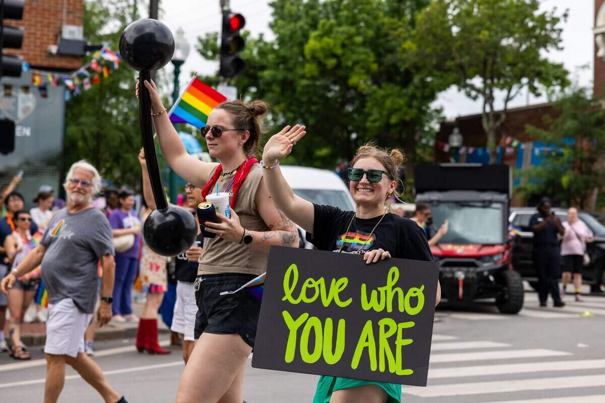 Parade attendee holds a sign and waves to the crowd during Kansas City's Annual Pride Parade at Westport Rd on Saturday, June 6, 2026.