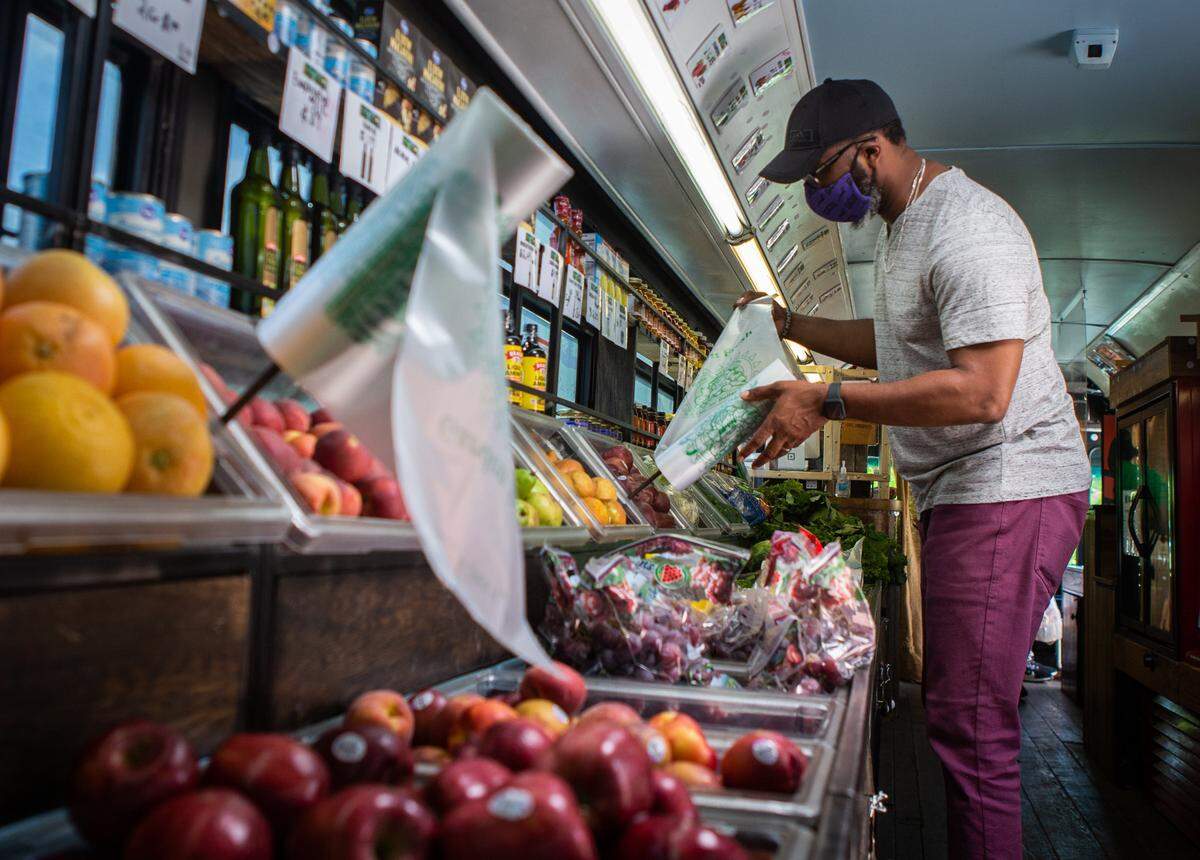 St. Louis Metro Market customer, Will Smith, grabs a bag to pack with fresh fruit or veggies while shopping on the market bus, parked at the Ferguson Community Empowerment Center on Friday, June 4, 2021. Smith works in the building, so shopping at the market is especially convenient. “Being able to come out here when I need fruit and veggies, and to get affordable prices, that’s what I like,” he said.