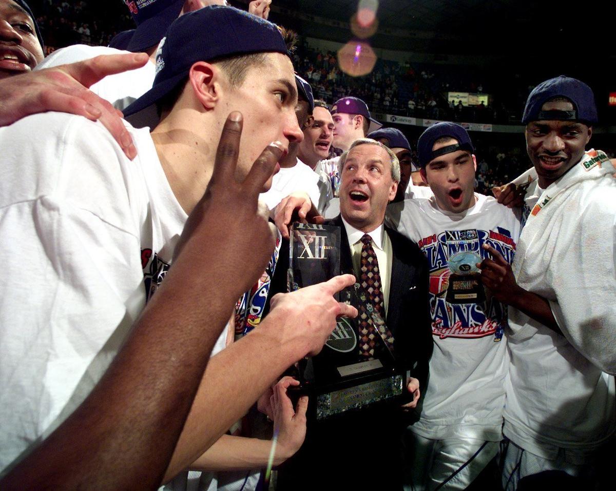 Surrounded by his players, and holding the coveted hardware, KU head coach Roy Williams celebrates the Jayhawks Big 12 Tournament Championship victory over Oklahoma State in 1999 at Kemper Arena. The Jayhawks won, 53-37.