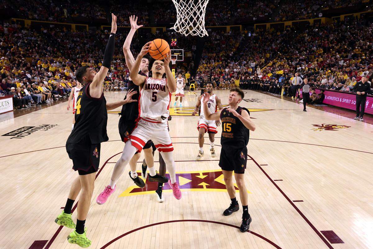 Brayden Burries #5 of the Arizona Wildcats drives to the basket against Andrija Grbović #14 and Santiago Trouet #1 of the Arizona State Sun Devils during the second half at Desert Financial Arena on January 31, 2026 in Tempe, Arizona.