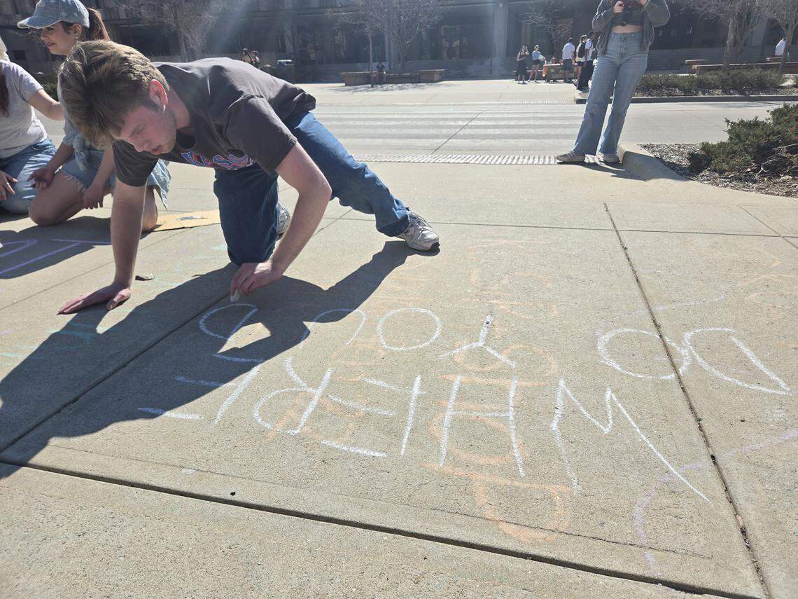 A University of Kansas student writes message on the sidewalk outside of Strong Hall in protest of an ICE detainment on the morning of Feb. 27.