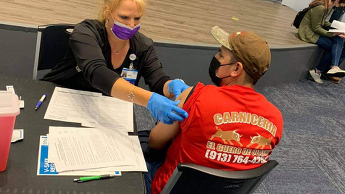 A volunteer from Olathe Health helps distribute Covid vaccines during at event at Center of Grace.