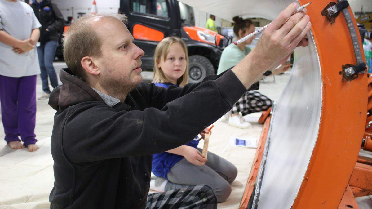 Clint Childs helps his daughter, Katie Childs, sketch her design on a snow plow as part of the snOlathe plow art contest.