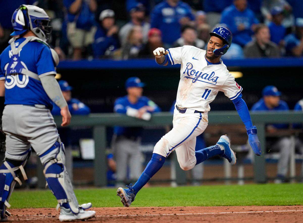 Kansas City Royals third base Maikel Garcia (11) scored a run against Toronto Blue Jays catcher Alejandro Kirk (30) during the fifth inning at Kauffman Stadium on April 23, 2024, in Kansas City, Missouri.