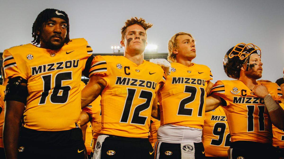 Missouri football players (from left to right) Johnny Walker Jr., Brady Cook, Sam Horn and Barrett Banister lock arms as Marching Mizzou plays “Old Missouri” on Oct. 22, 2022, at Faurot Field in Columbia, Mo.