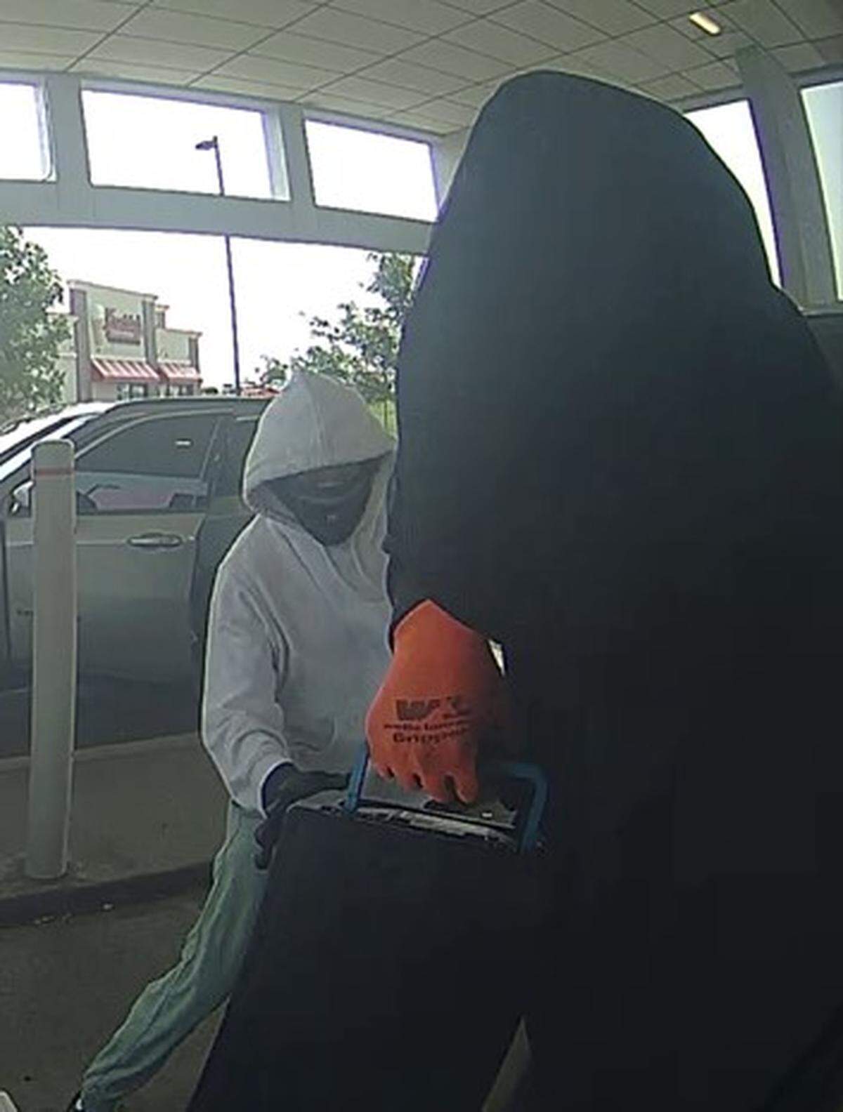 Two masked men approached a victim “working on” an ATM and fled with cash, according to the FBI.