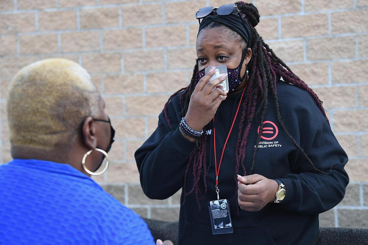 Rashonda Johnson explains to a resident how to administer Narcan Nasal Spray to treat an overdose. Johnson was one of the “Serving Our Streets” team members working at a weekly street outreach event in front of a gas station on North Kingsway Boulevard in St. Louis.