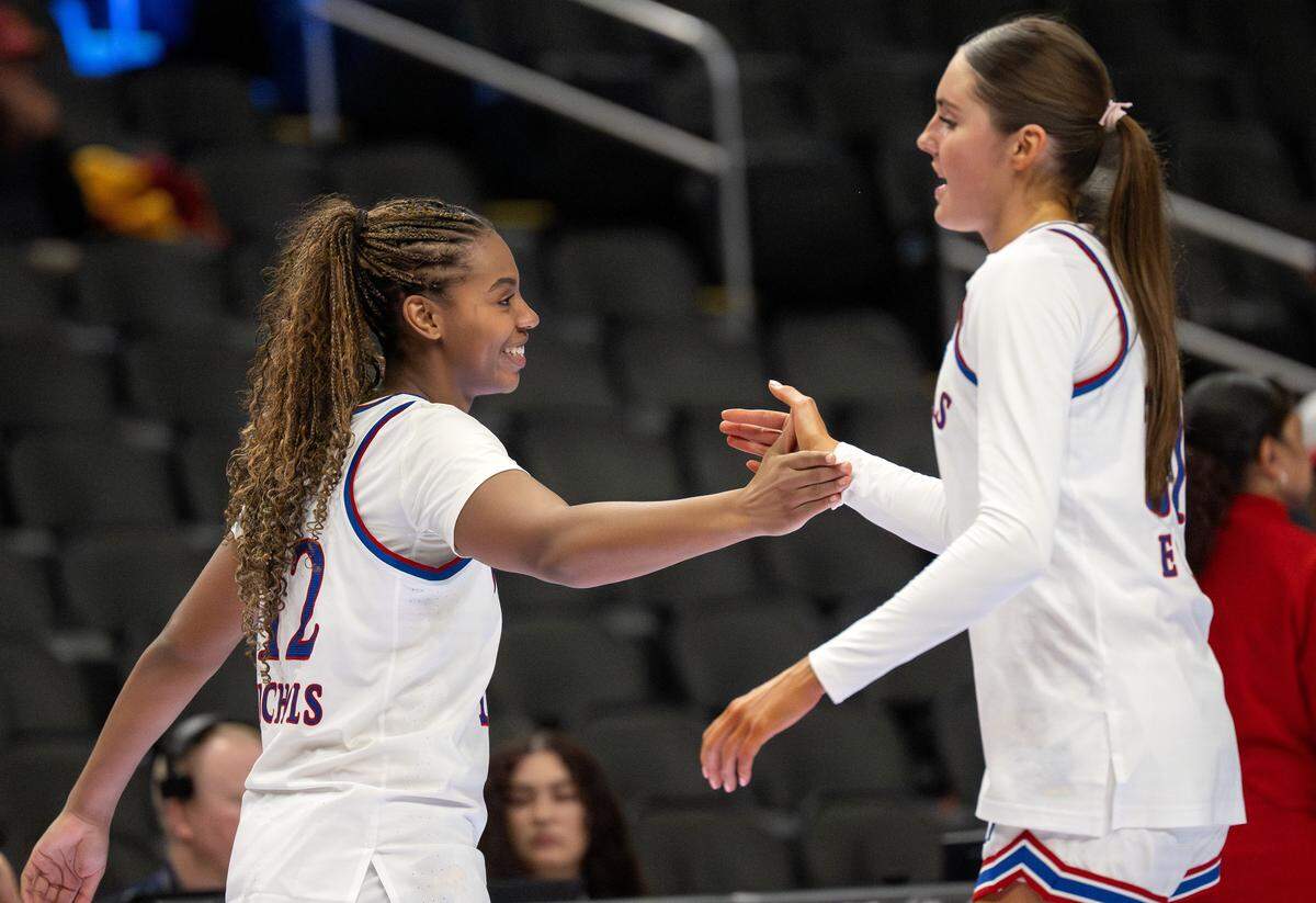Kansas Jayhawks guard S'mya Nichols (12) high-fives guard Elle Evans (21) after defeating the UCF Knights 56-35 in the Big 12 Women's Basketball Tournament at T-Mobile Center on Wednesday, March 4, 2026, in Kansas City.