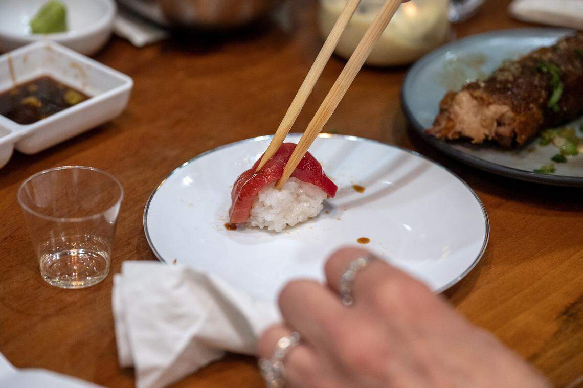 A guest eats freshly prepared bluefin tuna nigiri with chopsticks during a cutting show at KC Craft Ramen on Monday, March 2, 2026, in Overland Park.