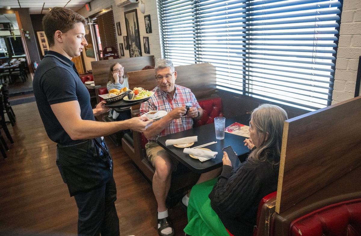 Server Wyatt Burnett delivers bread and salad to lunch time diners at Toni’s Italian Restaurant, 1808 E Santa Fe St., in Olathe. The restaurant is planning to move as the city works on acquiring it to make way for the major I-35/Santa Fe corridor project.