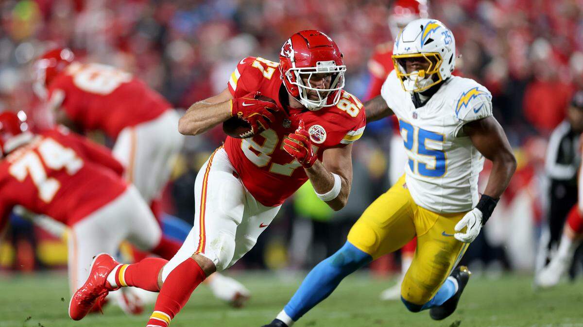 Travis Kelce #87 of the Kansas City Chiefs is chased by Junior Colson #25 of the Los Angeles Chargers during the second quarter at GEHA Field at Arrowhead Stadium on December 8, 2024 in Kansas City.