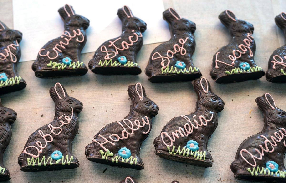 Handmade chocolate Easter bunnies, personalized with names in white chocolate, dried after being lettered at Laura Little’s Candies in Prairie Village. The personalized chocolate bunnies, eggs and Easter baskets remain a beloved tradition for generations of families.