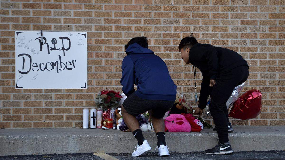 Family and friends of a teen who was fatally shot inside a Kansas City, Kansas, laundromat stopped by to add to a memorial in front of the building on Nov. 16, 2017. The slain teen’s brother, 14-year-old Kyaw Wah (right) and another young man placed flowers at the site.