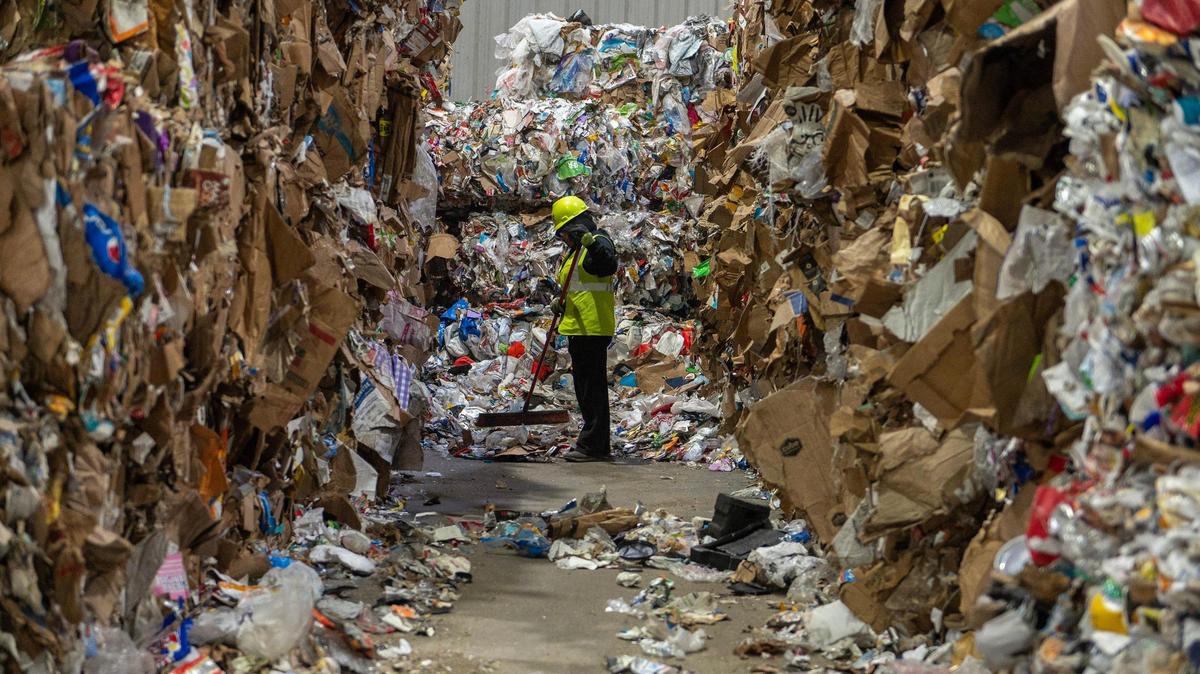 A GFL employee sweeps recycled materials from the ground at the GFL Materials Recovery Facility on Tuesday, March 28, 2023, in Harrisonville, Mo.