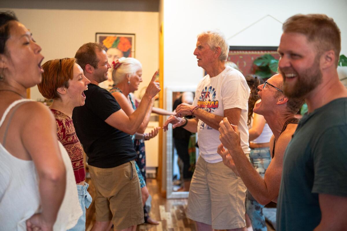 Laughter yoga students participate in a laughing role play performance at Cafe Gratitude. Laughter yoga requires no yoga mat and is accessible to all ages and body types.