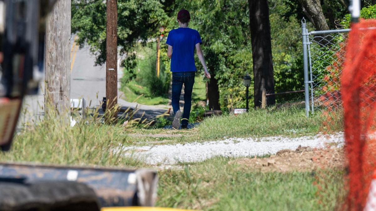 A resident walks along the worn sidewalks on North Cleveland Avenue near the Chaumiere neighborhood on Monday in Kansas City.