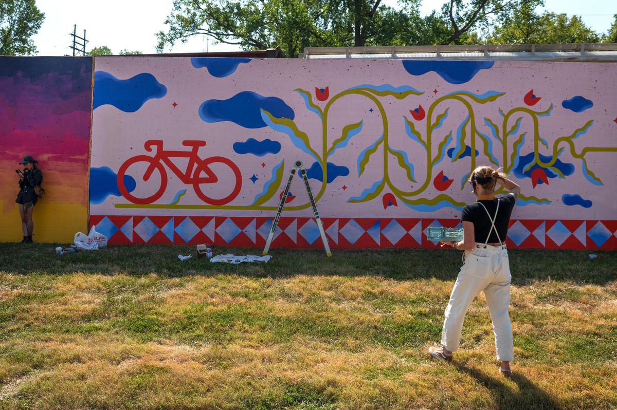 Emily Ding, left, designs her mural while Felicia Koloc steps back after putting the finishing touches on her mural “Joy Ride” on Friday, Sept. 15, 2023, at the Riverfront Heritage Trail in Kansas City. “It seems to be like the basic reason we exist is to be together as a community and have spaces where you can interact with people,” Koloc said. “Art, historically, always has done a good job of bringing people together.”