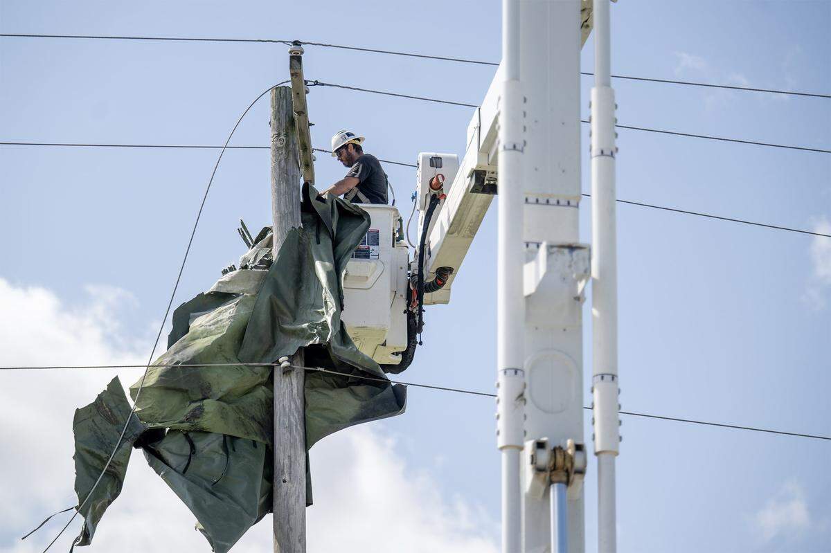 A utility worker from Gardner, Kansas, untangles debris lodged in the power lines on Tuesday, April 14, 2026, in Ottawa, Kansas. The town was hit by a tornado Monday night.