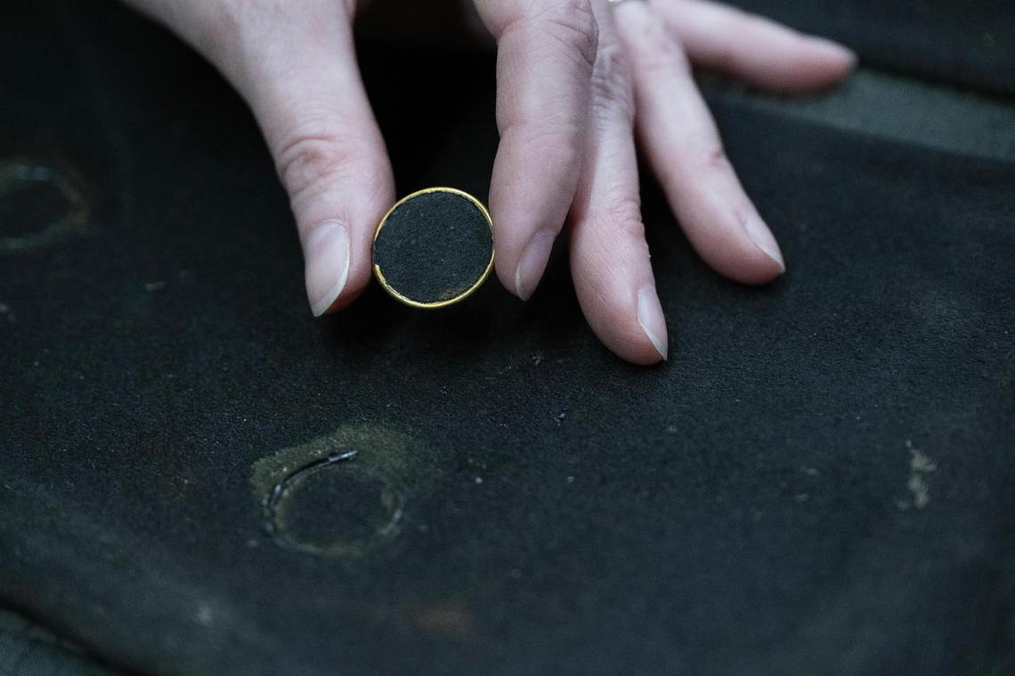 Textiles conservator Holly Messinger displayed a deteriorated button from a men’s frock coat she was preserving at the Arabia Steamboat Museum in Kansas City on Thursday, April 18, 2025. Recovered from the steamboat in 1988, the coat had been stored in a freezer awaiting preservation.