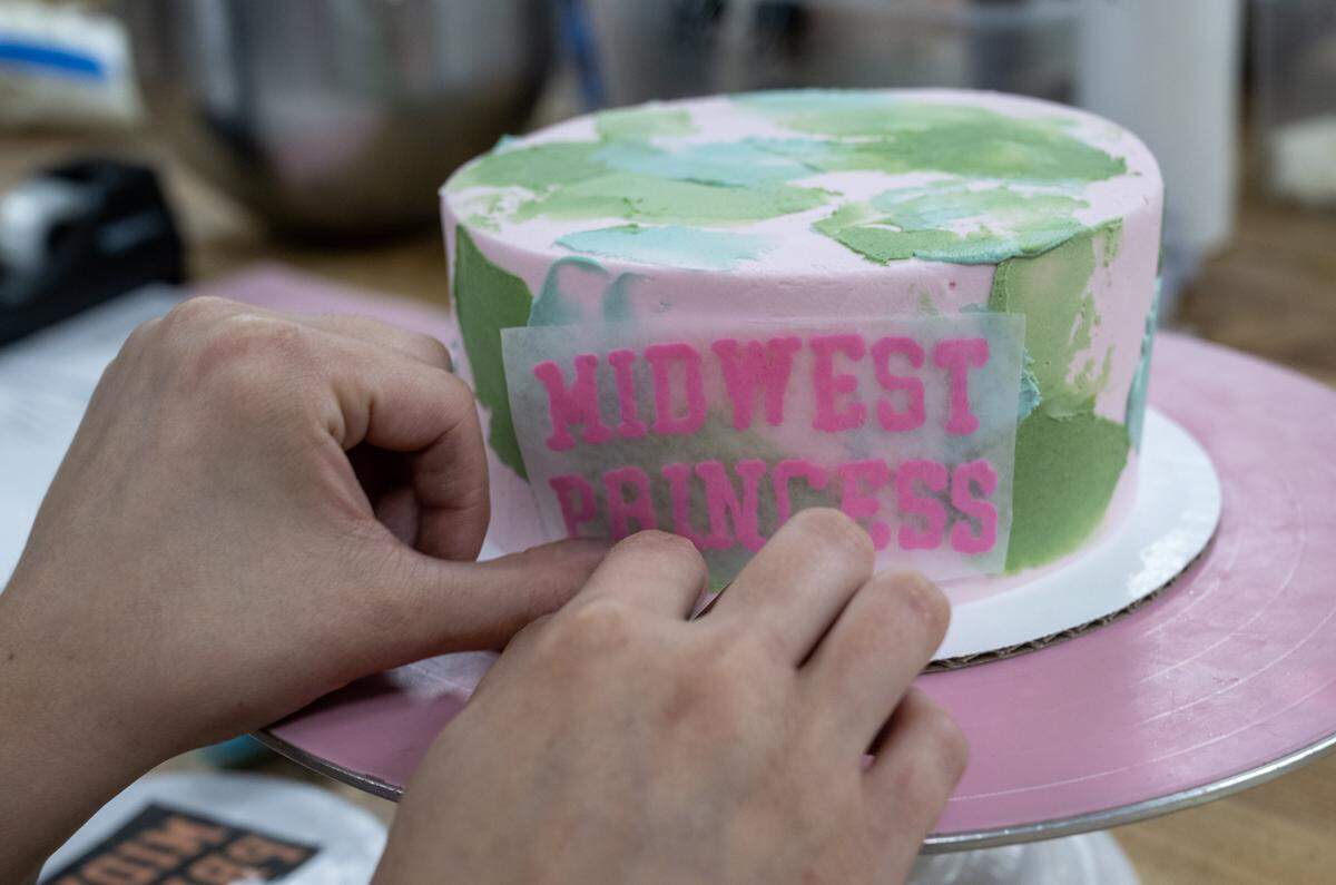 Cake decorator Hannah Finch applies “Midwest Princess” to a Chappell Roan-themed cake she was making at McLain's Bakery in Waldo on Thursday, October, 2, 2025. Local bakeries are seeing a significant demand for cookies to celebrate pop stars Taylor Swift and Chappell Roan.