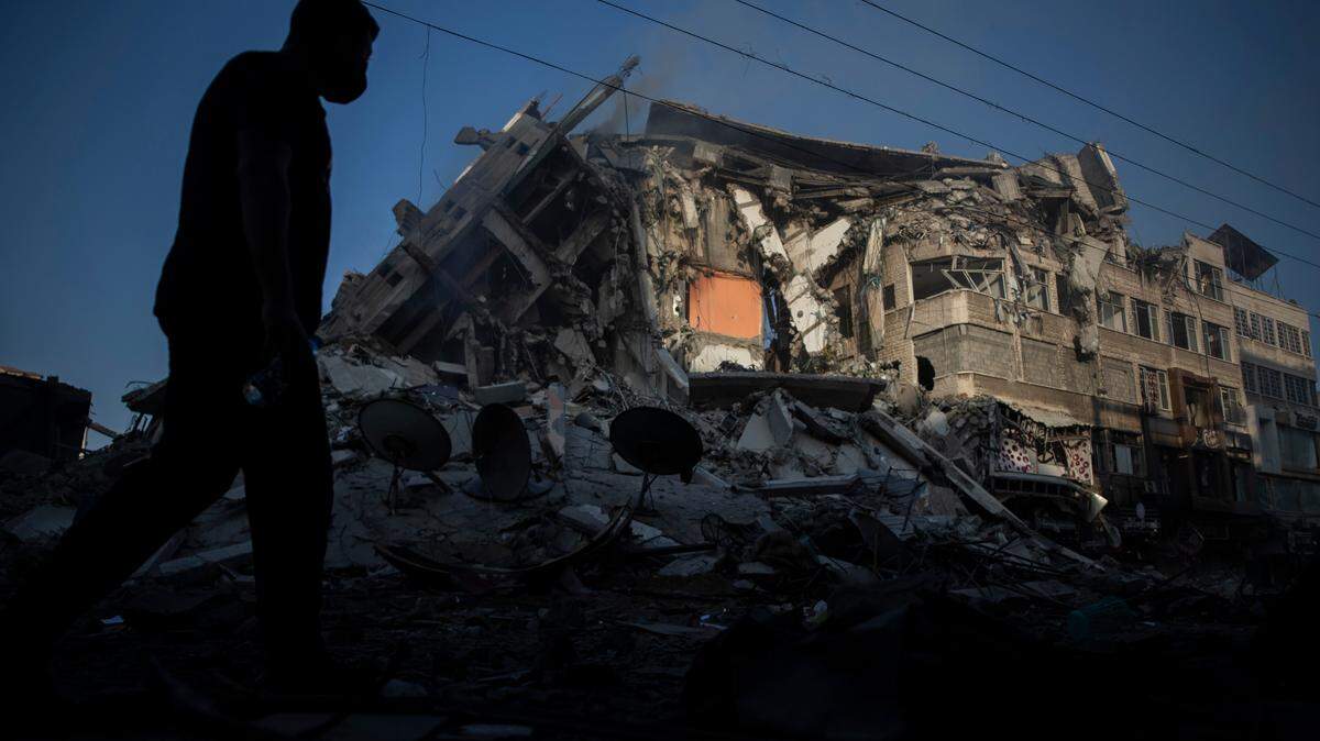 Palestinians walk next to the remains of a destroyed 15 story building after being hit by Israeli airstrikes on Gaza City, Thursday, May 13, 2021.