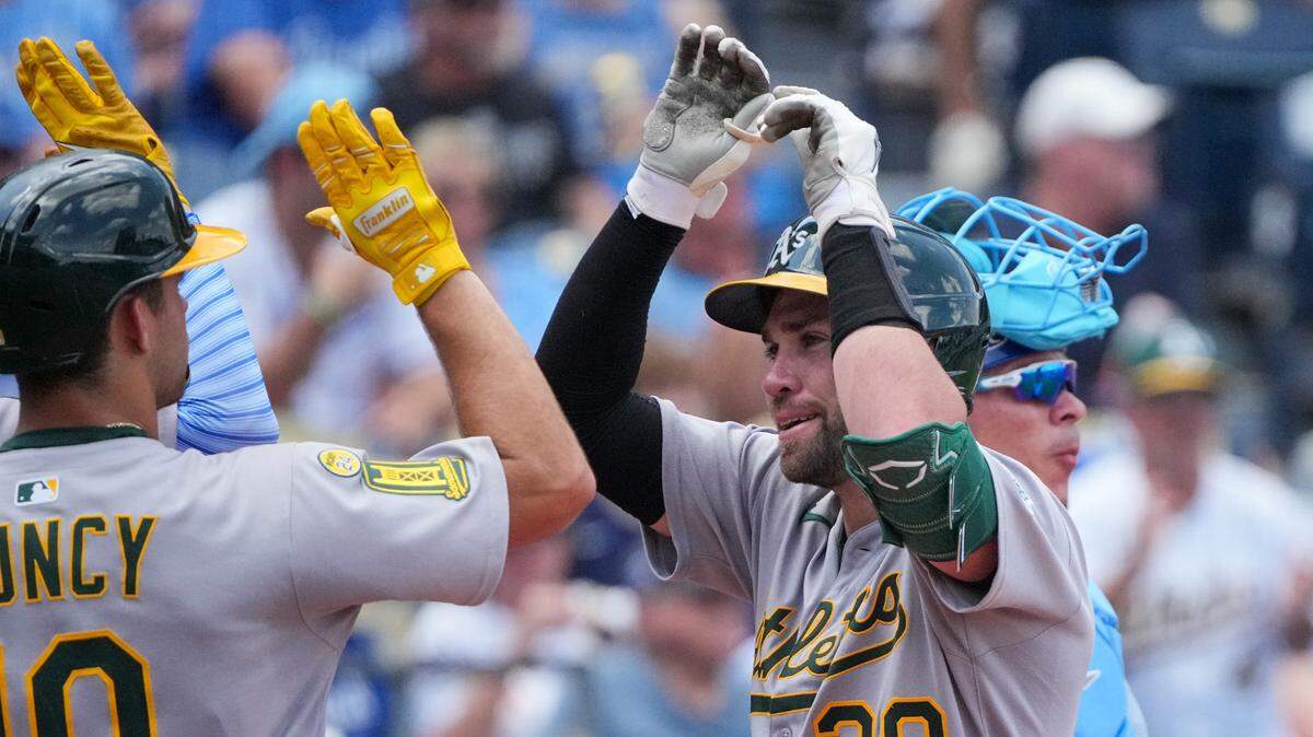 Oakland Athletics catcher Austin Wynns celebrates a home run with third baseman Max Muncy, with Royals catcher Freddy Fermin at far right in the background, on Sunday, June 15, 2025 at Kauffman Stadium in Kansas City.