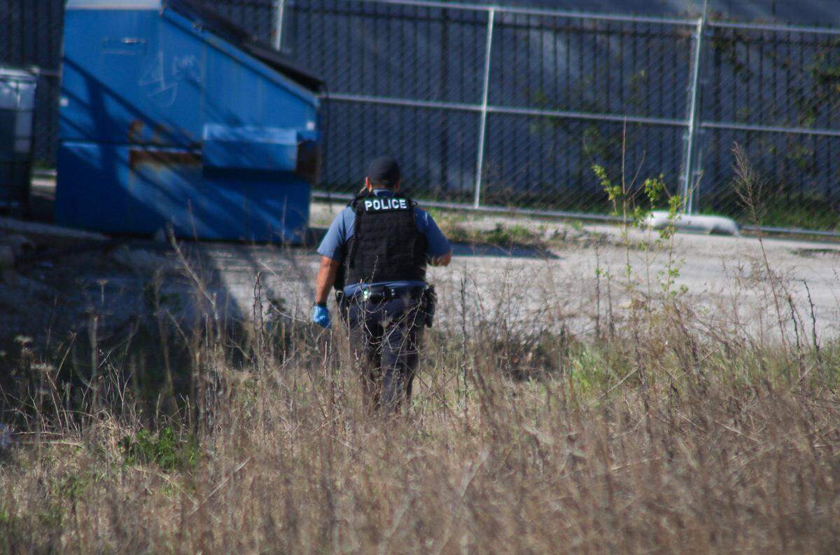 A police officer searches the area of Troost and 81st Street in Kansas City after a 911 call about a bone that looked human. The group was looking for missing person T’Montez Hurt close to where he was last seen.