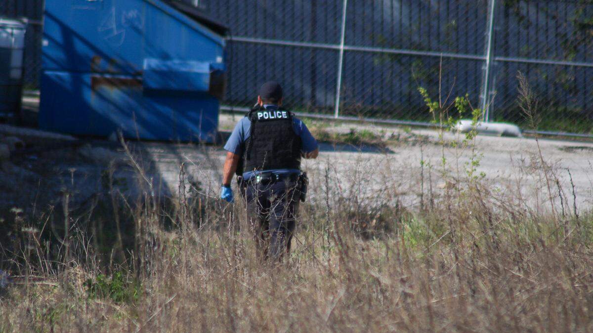 A police officer searches the area of Troost and 81st Street in Kansas City after a 911 call about a bone that looked human. The group was looking for missing person T’Montez Hurt close to where he was last seen.