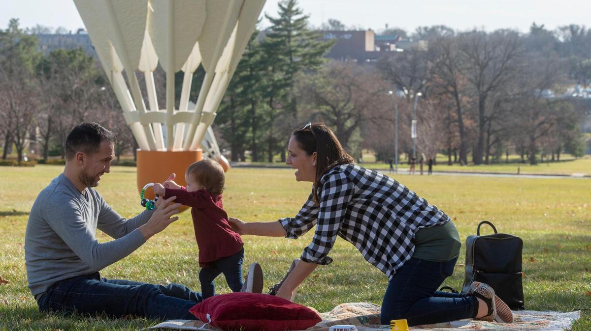 Jesus and Jennifer Clavo enjoy warm weather with their daughter, Camila, beneath a shuttlecock sculpture outside the Nelson-Atkins Museum of Art.