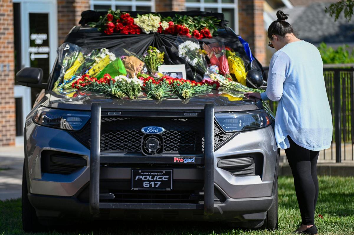 One day after North Kansas City Police officer Daniel Vasquez was fatally shot, a member of the community stop to pay tribute to the fallen officer whose police vehicle was laden with flowers on Wednesday, July 20, 2022, outside the North Kansas City Police Department. The woman, who asked that her name not be used, said she had a cousin who was a police officer who was also murdered.
