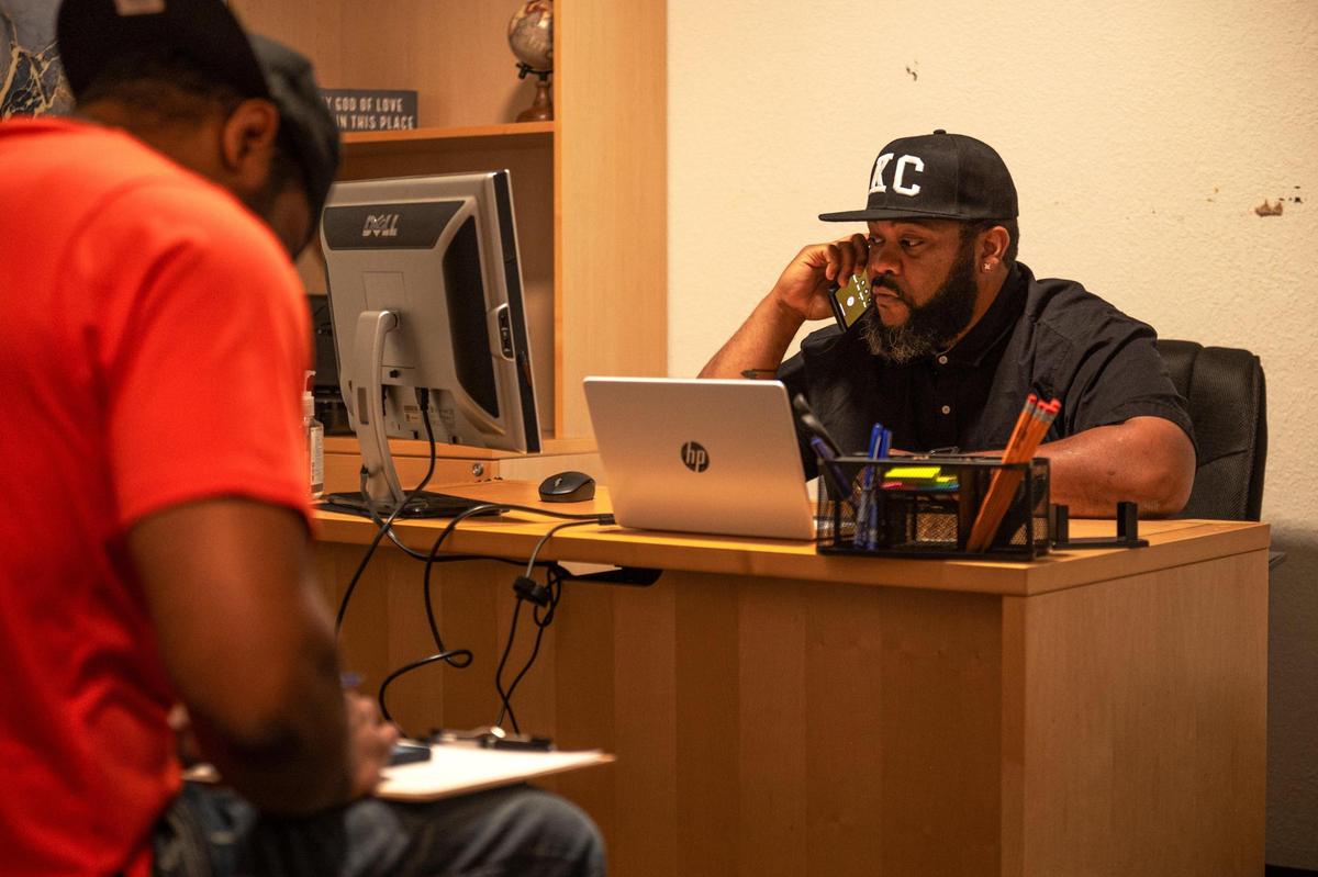Ronald Clark, left, fills out a job placement form while Andre Harris talks on the phone about a felony expungement at Dads Against Crime in Kansas City.