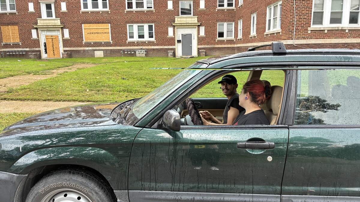Richard Flores, in the passenger seat, sits in his vehicle outside his apartment building on North Lawn Avenue. Flores said his family had to live in the car for four weeks after the power to the building was cut off.