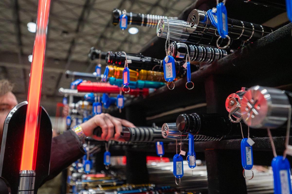 Visitors browse light sabers displayed in cubby-like shelves, including one priced at $349, during Planet Comicon at the Kansas City Convention Center on Saturday, March 22.