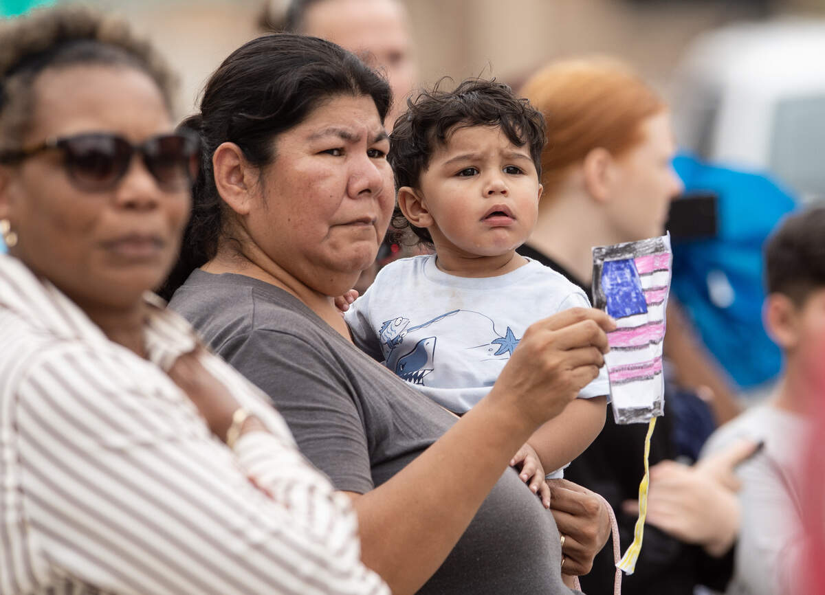 Frances Damian, holds her grandson, Luciano Garcia, 1, and a hand-drawn and colored American flag while watching the funeral procession for Wyandotte County Sheriff's deputy Elijah Ming go through downtown Kansas City, Kansas, on Monday, August 11, 2025.