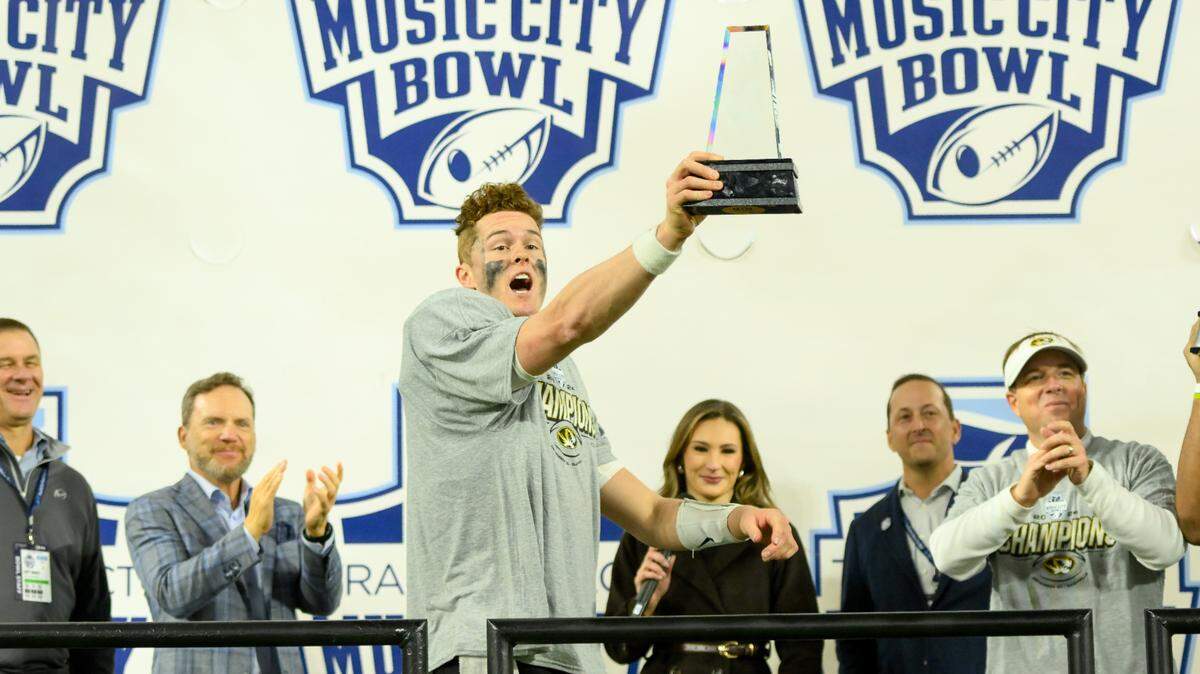 Missouri Tigers quarterback Brady Cook (12) holds his MVP trophy as he points to his team after defeating the Iowa Hawkeyes at Nissan Stadium on Dec. 30, 2024.