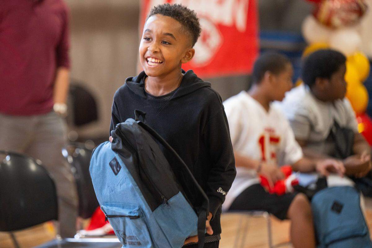 Fifth grader Jayvon Legrone shows off his new backpack signed by KC Wolf and Kansas City Chiefs cornerback Trent McDuffie at Gordon Parks Elementary School during a meet & greet and backpack drive on Monday, Aug. 25, 2025, in Kansas City. In addition to signing autographs, McDuffie donated the backpacks, which also included water bottles and school supplies, to 150 kids at the school through his T22 McDuffie Foundation.