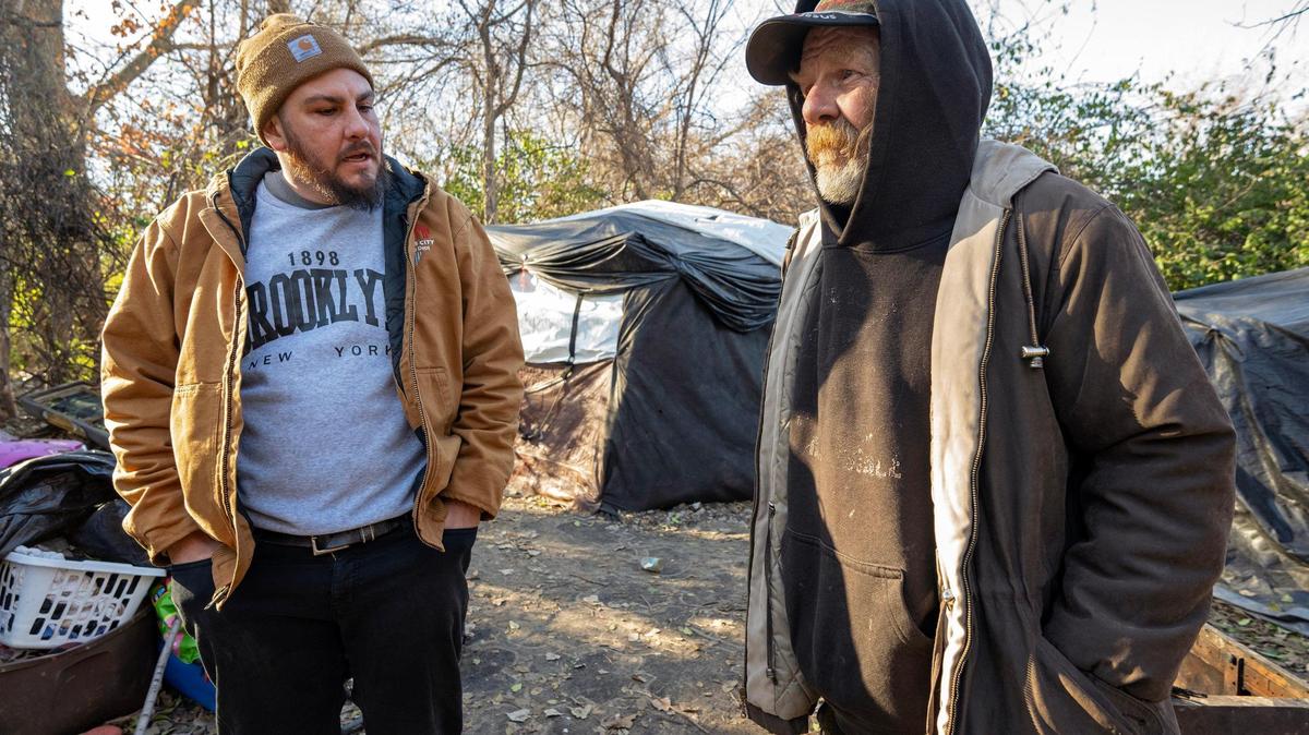 On a cold December morning, Nick Allen, left, the street outreach coordinator for the Office of Unhoused Solutions, visits with Bill, 67, who is working to get out of homelessness.