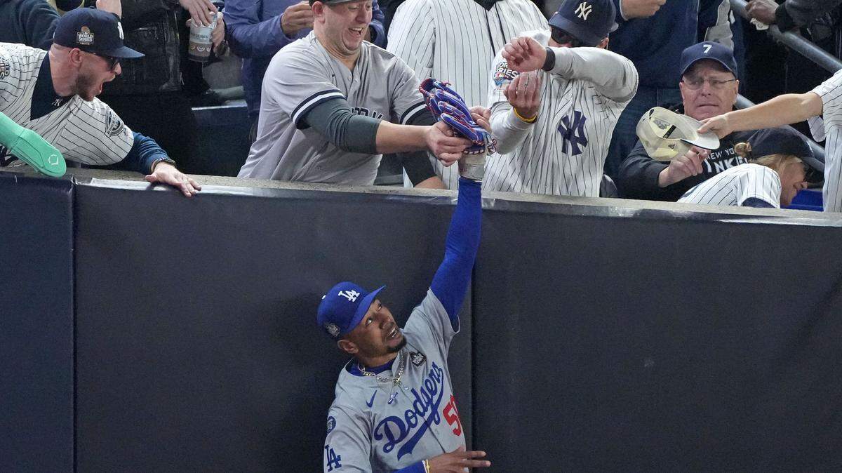 Yankees fans interfere with Los Angeles Dodgers outfielder Mookie Betts (50) in the first inning during Game 4 of the 2024 MLB World Series at Yankee Stadium.