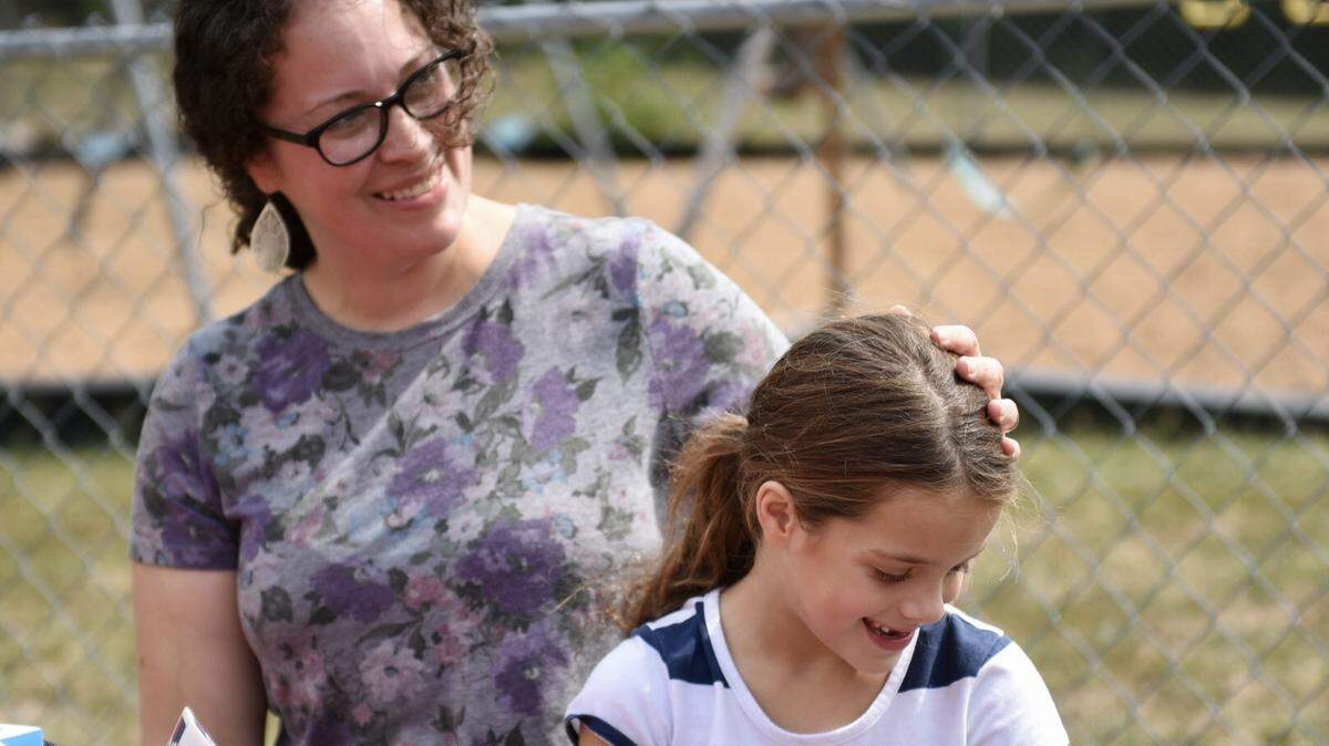 Megan Criniere, the widow of Grandview middle school teacher Charles Criniere, sits with her 6-year-old daughter, Ava, on Sept. 15, 2022, outside Grace Point Baptist Church where Charles Criniere was a deacon. The couple has 10 children, 9 of whom still live at home.