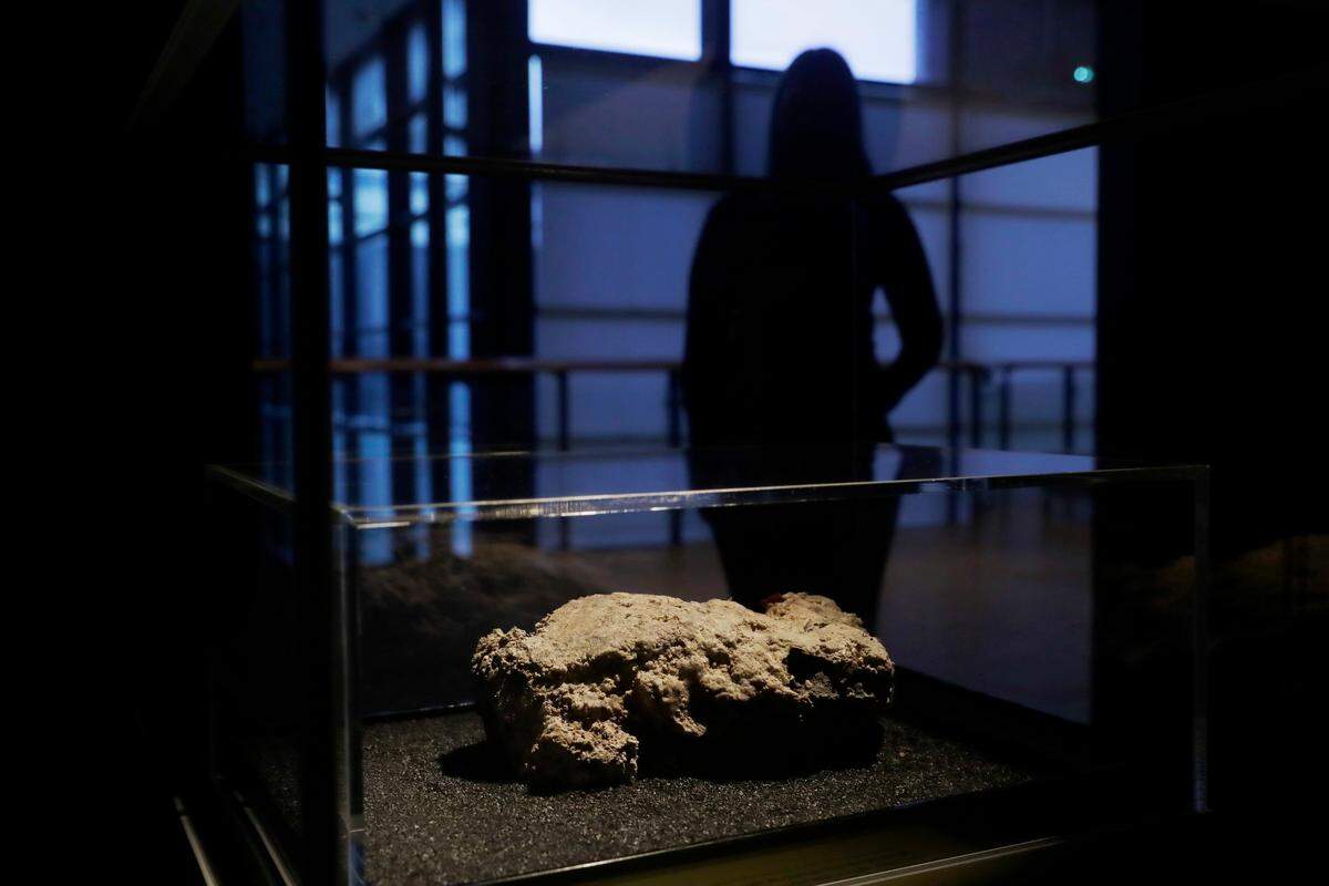A staff member poses for photographs next to the only remaining piece of the 130 ton, 250 meter long fatberg, removed from the sewers in the Whitechapel area of east London in the latter months of 2017, displayed during a media preview at the Museum of London in London, Thursday, Feb. 8, 2018.