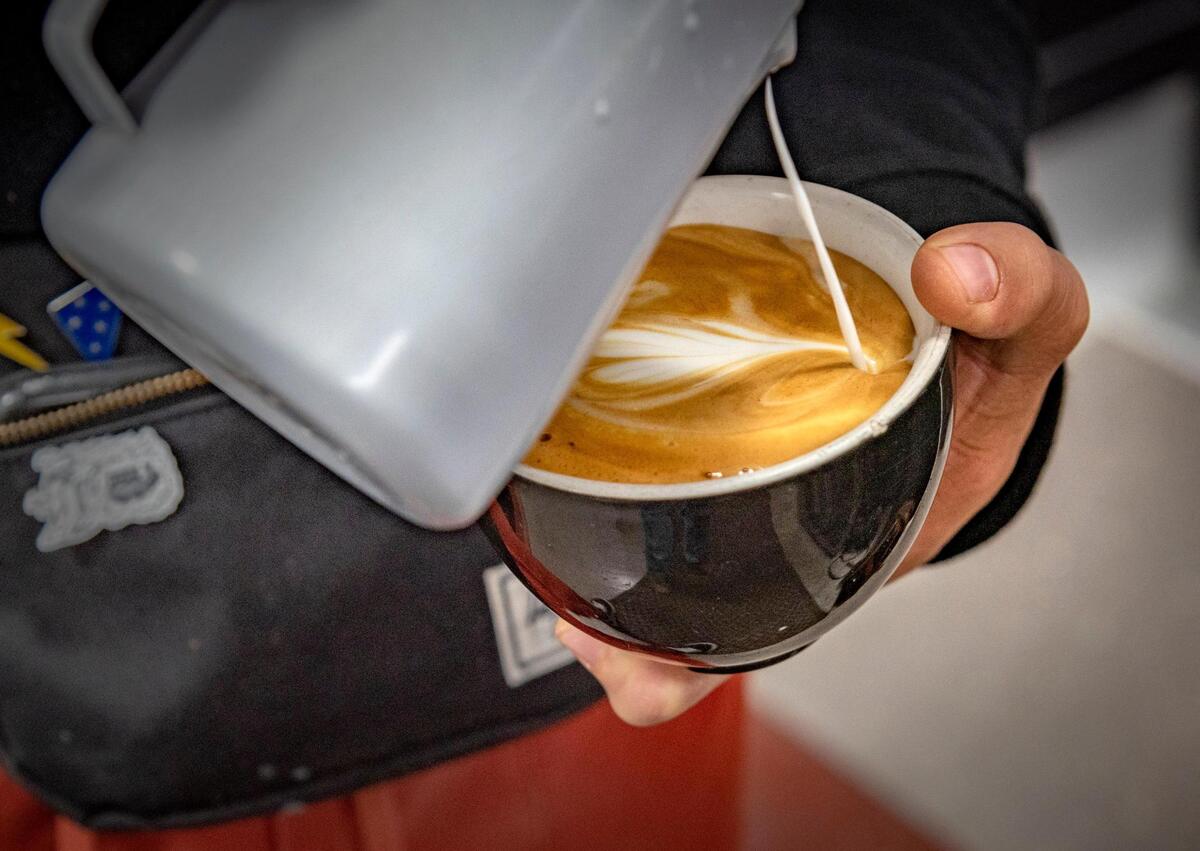 Kinship Cafe owner T.J. Roberts creates the signature coffee design.