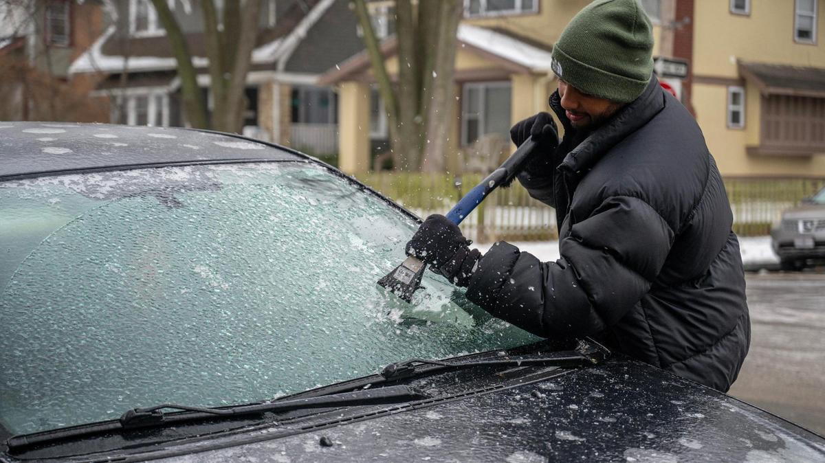 Jason Lopez scrapes a layer of ice off his car windshield on Monday, Jan. 22, 2024, in Kansas City.