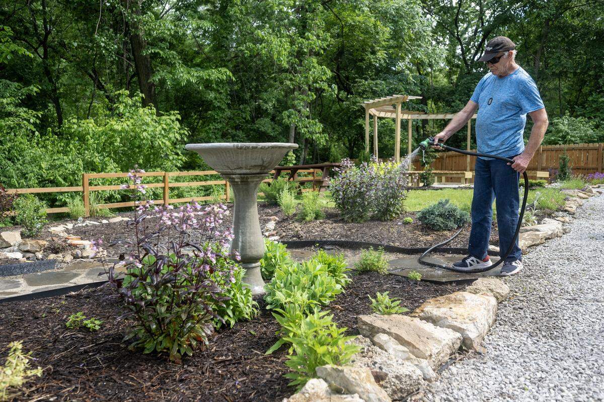 Paul Schnirch, 67, waters the community garden at Eden Village on Tuesday, May 12, 2026. Schnirch, a U.S. Army veteran and former mechanic, moved into the gated community at 1001 Metropolitan Ave. in July 2024. He said he inherited his mother's “green thumb” and enjoys the garden. The village provides permanent supportive housing for individuals transitioning from chronic homelessness.