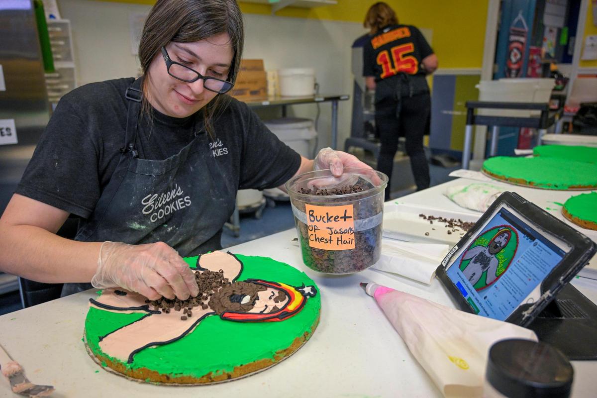 Hannah Stumpner, manager of&nbsp;Eileen’s Colossal Cookies in Liberty, adds a bit of “chest hair’ to a cookie cake she was making Thursday at the bakery. The chest hair is created from chocolate curls. 